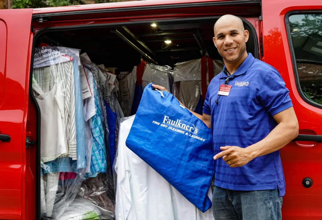 A man standing in front of a van with clothes in it.