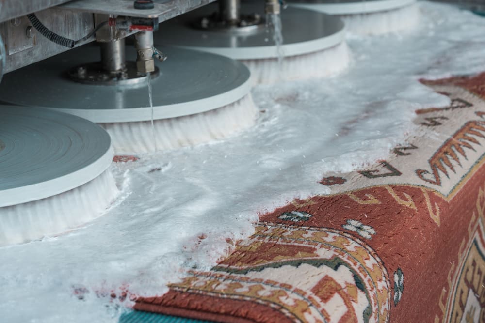 A rug being cleaned on a machine.