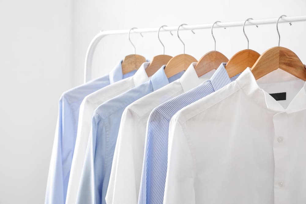White and blue shirts hanging on a rack.